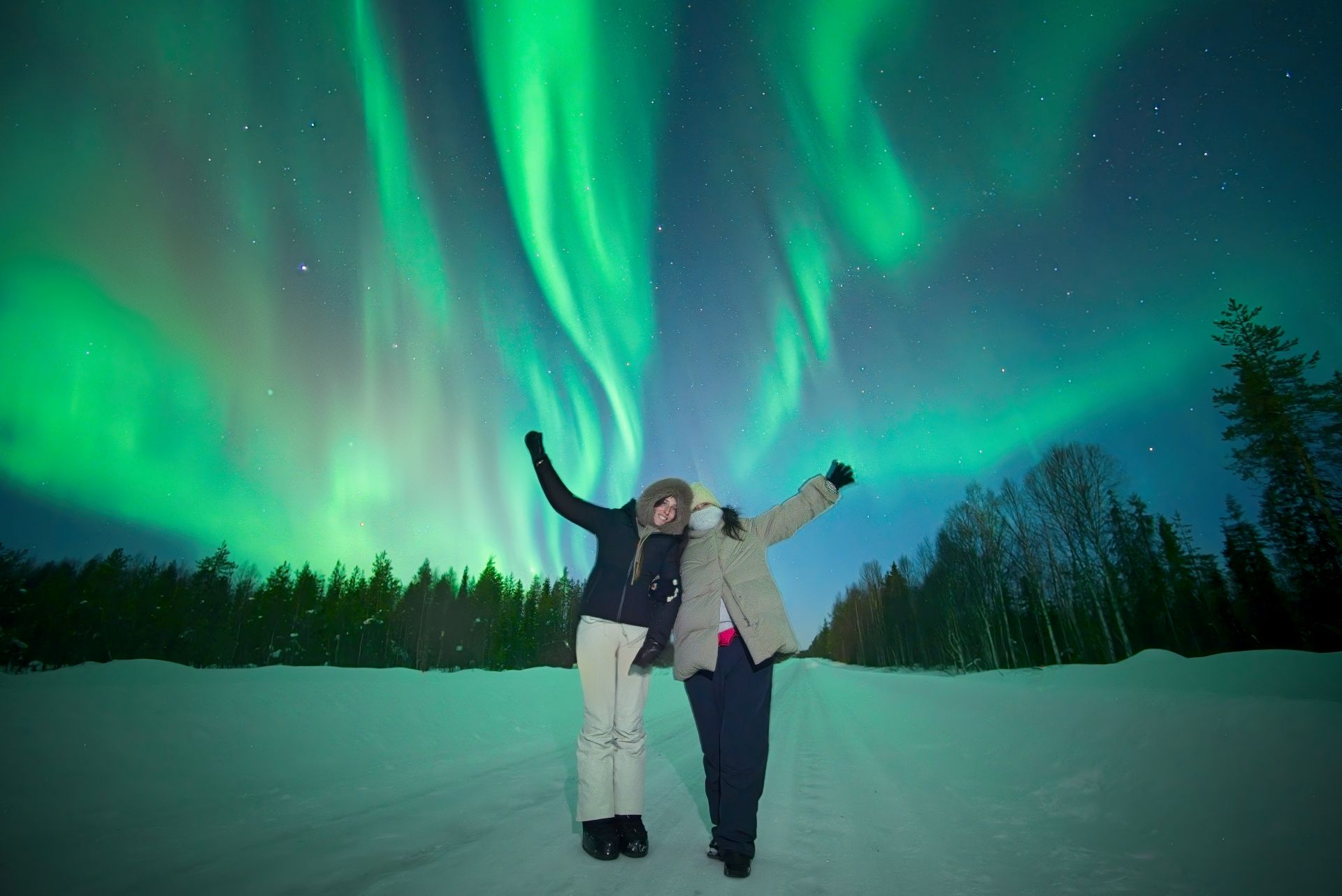 Two people under vibrant northern lights in Rovaniemi, Lapland, Finland