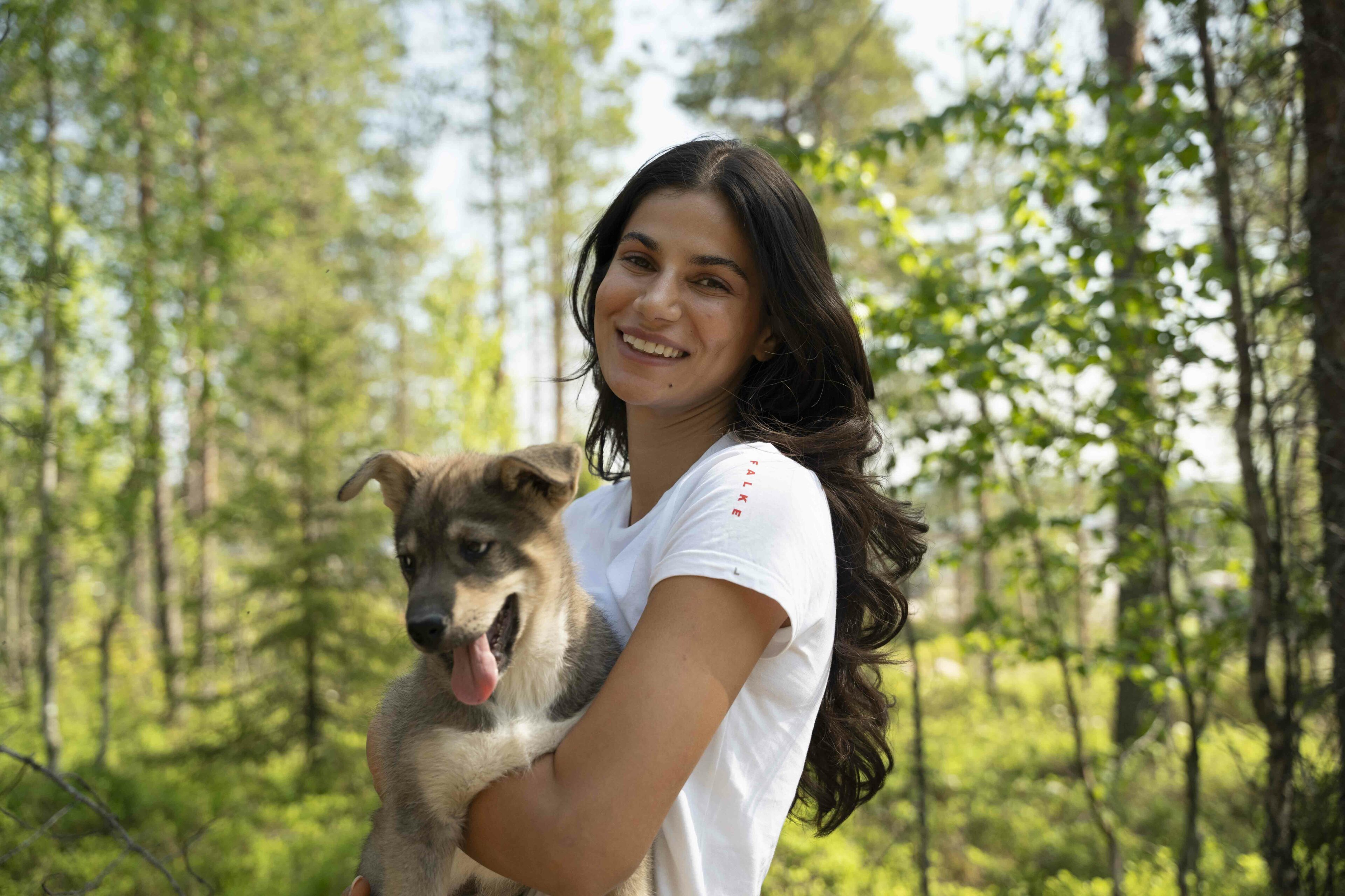 Woman holding a small husky puppy at Bearhill Husky Kennel in summer in Rovaniemi, Lapland, Finland