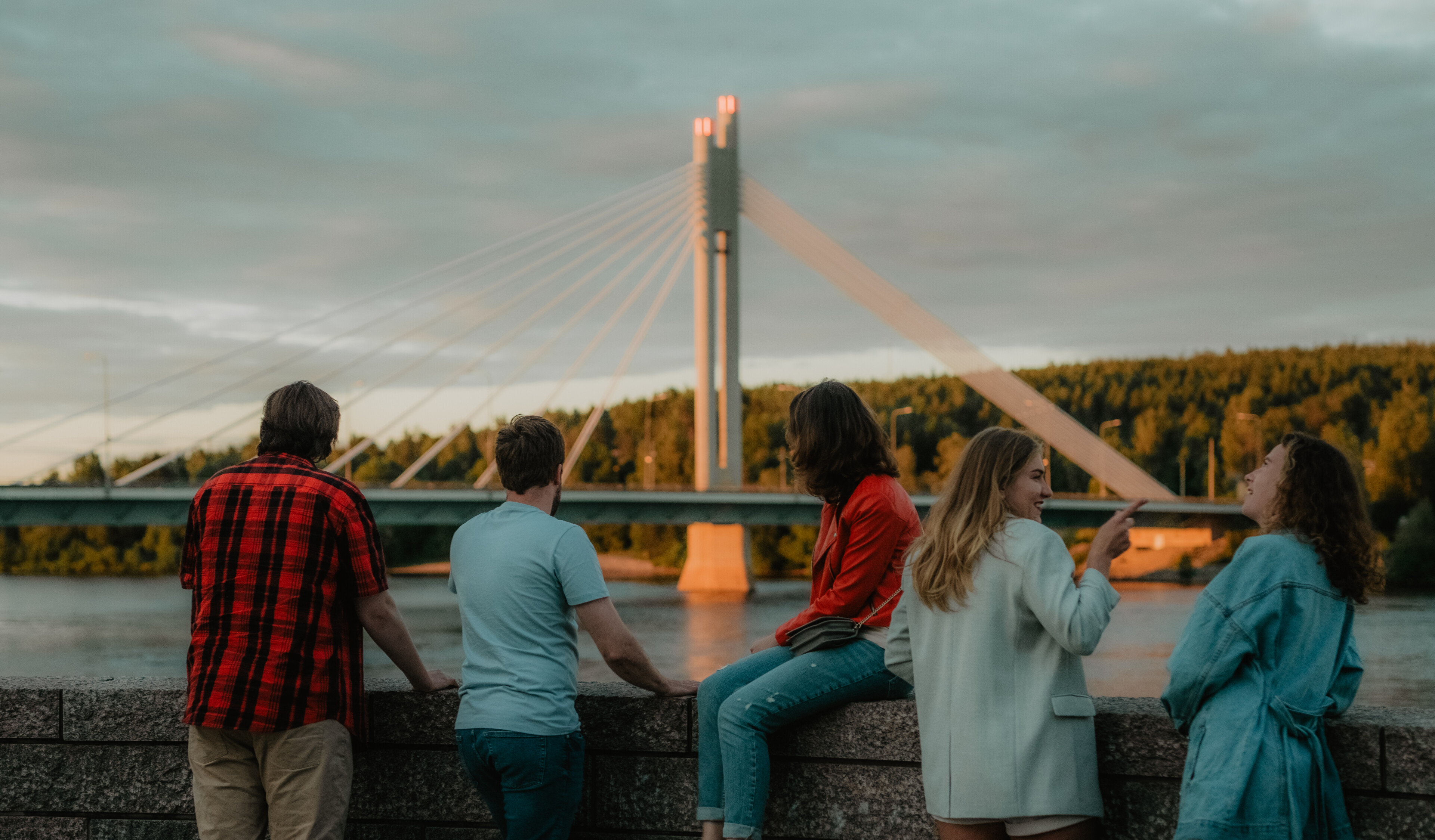 Ryhmä kavereita nauttimassa kesäillasta Kemijoen rannalla yöttömän yön aikaan Rovaniemellä, Lapissa.