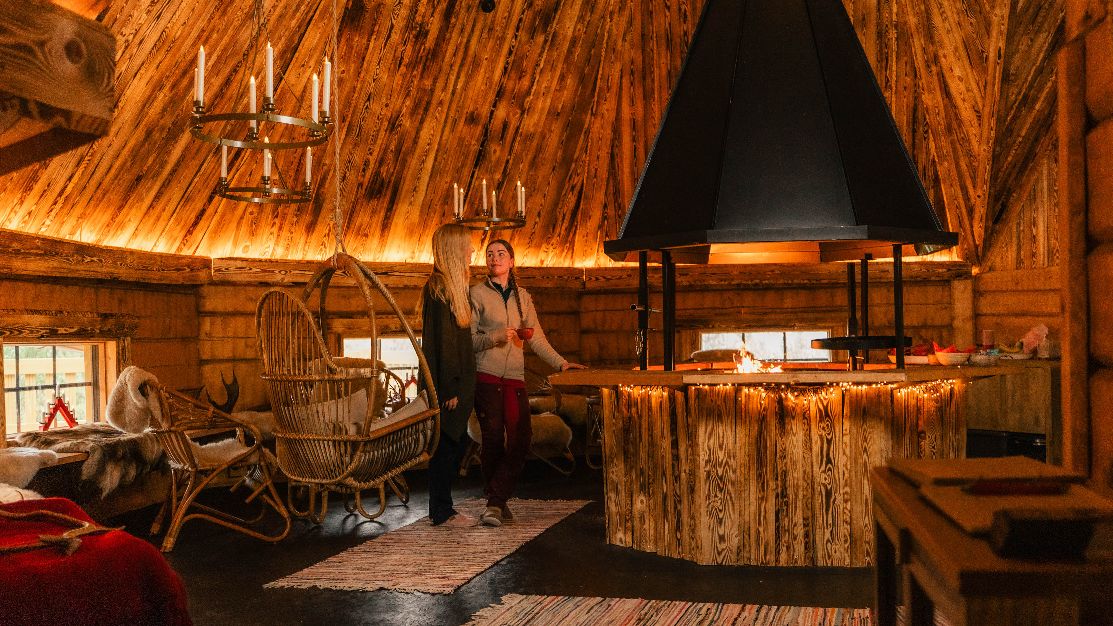Cozy interior with guests and fireplace at Taava Reindeer Farm, Rovaniemi.