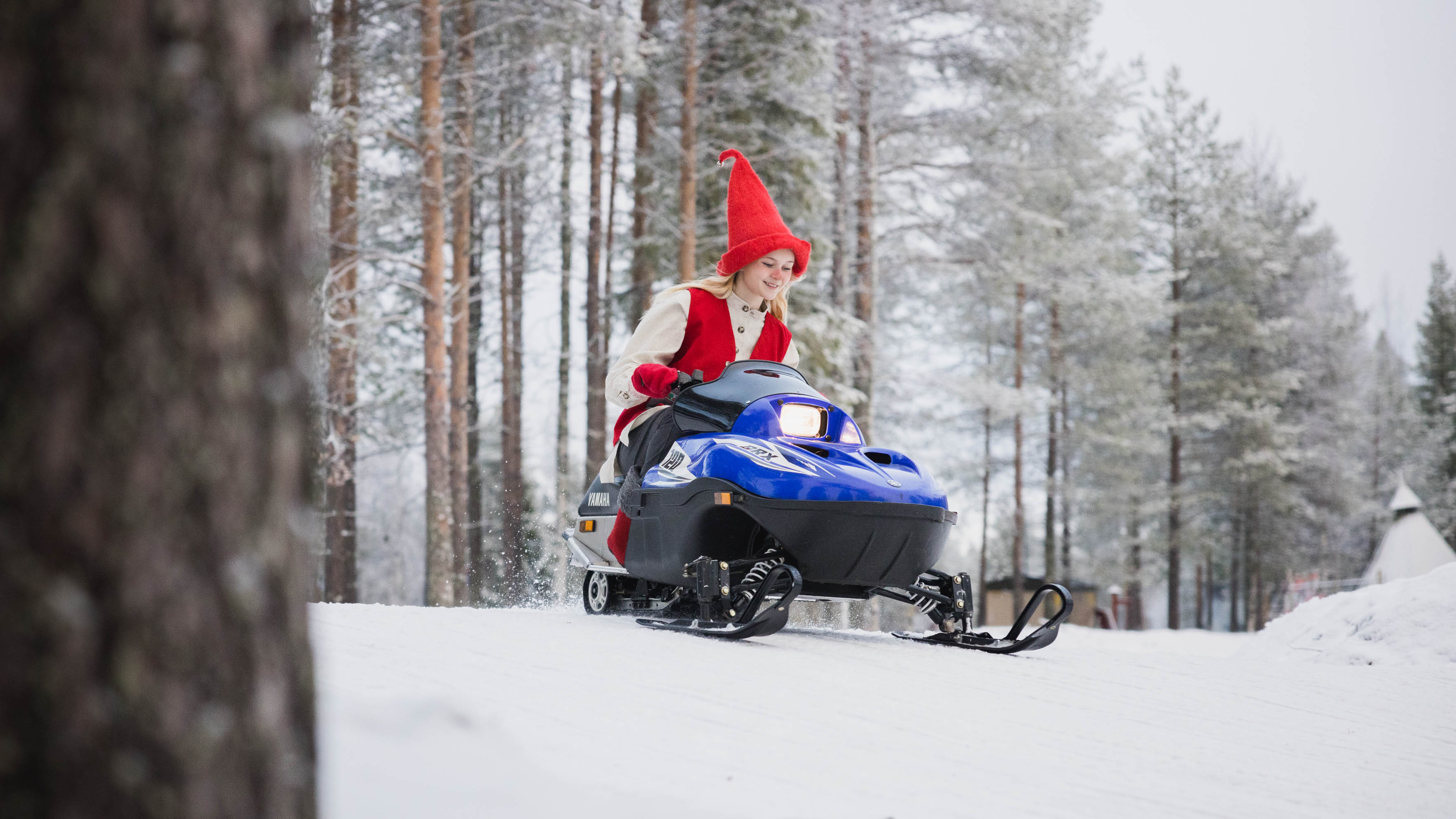 an elf on a mini snowmobile in snowy forest, Rovaniemi, Lapland, Finland