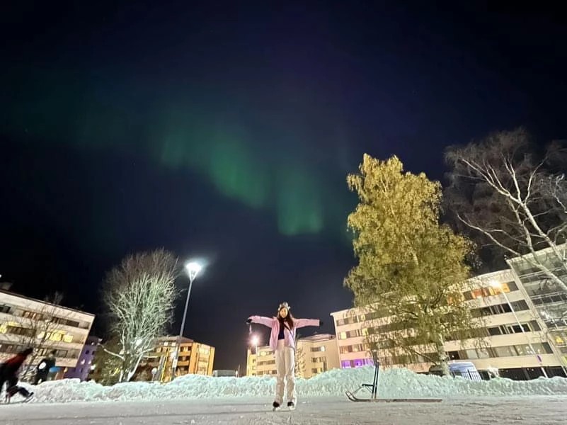 Person skating under northern lights at Naava Cafe.