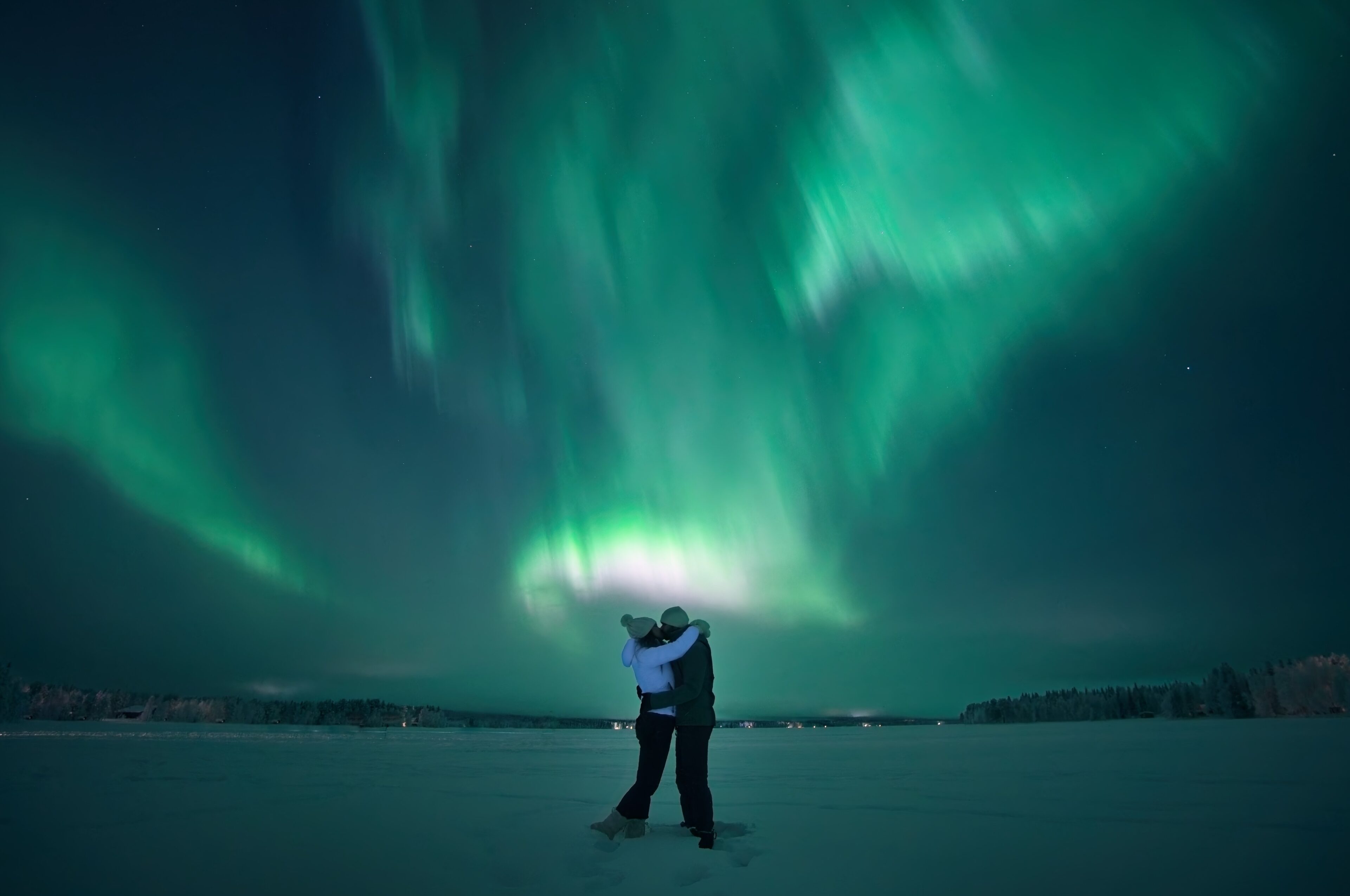 Couple embracing under northern lights in Rovaniemi, Lapland, Finland