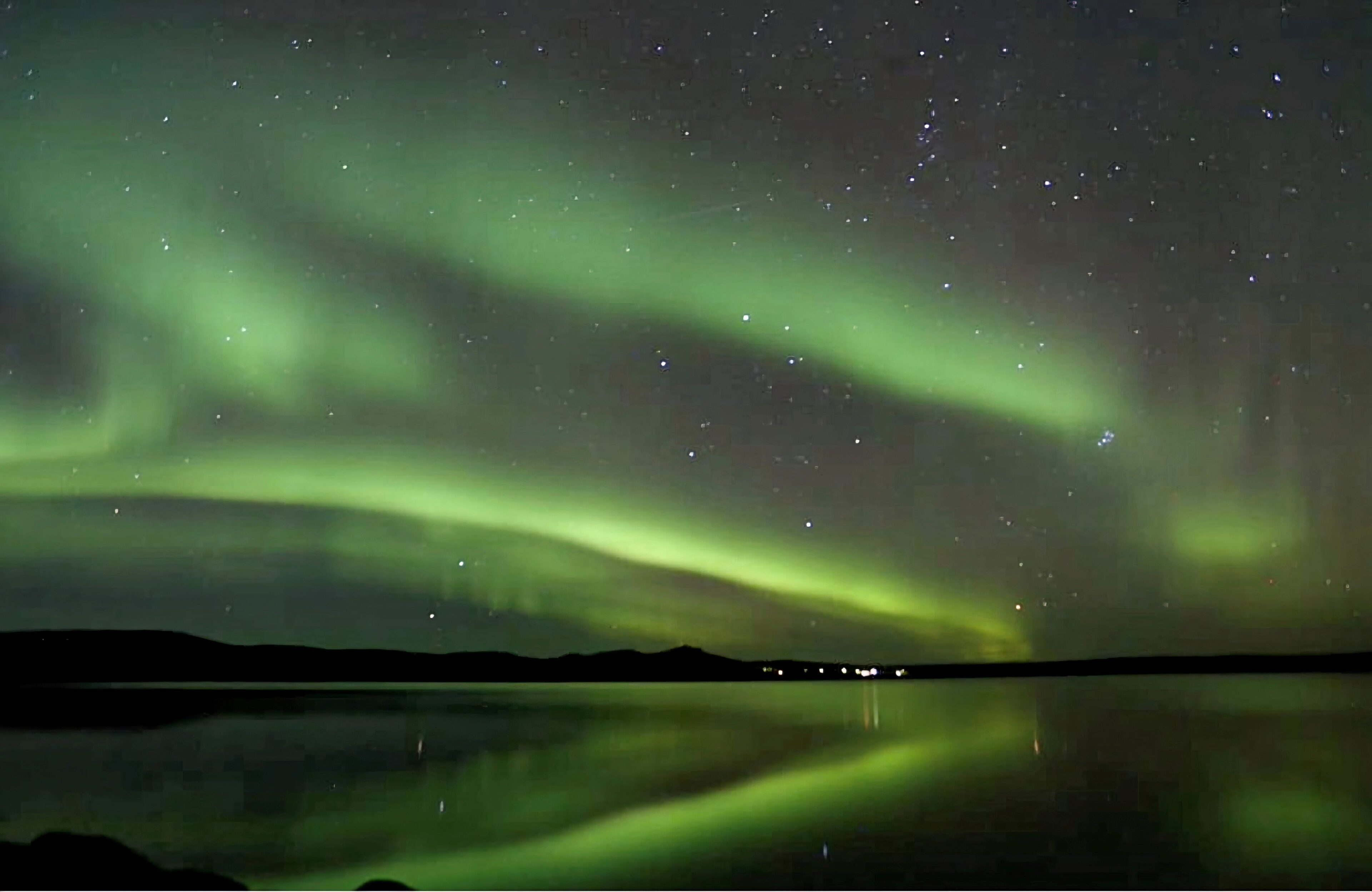 Vibrant auroras over water in Rovaniemi, Lapland, Finland.