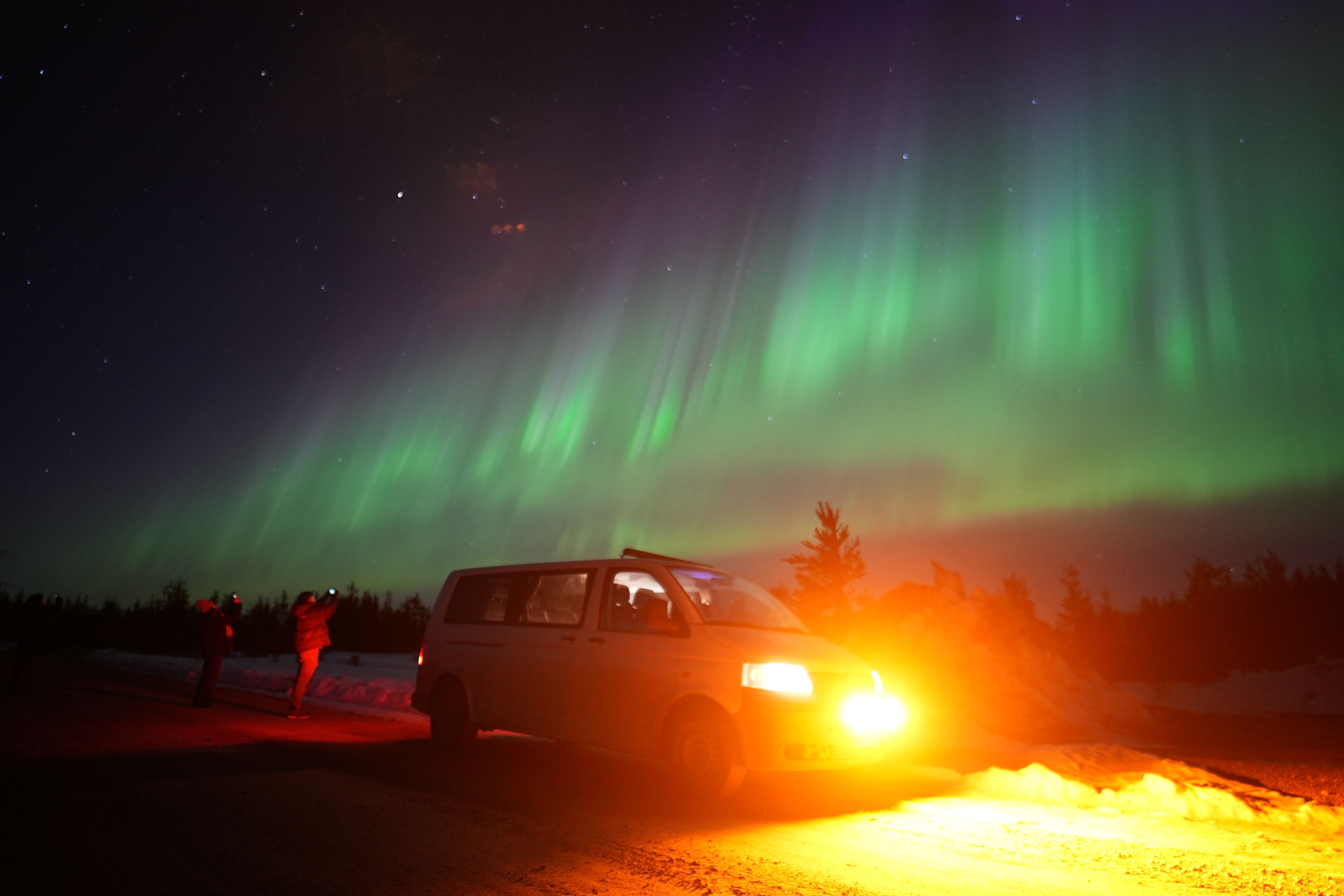 Van under vibrant northern lights in Rovaniemi, Lapland, Finland