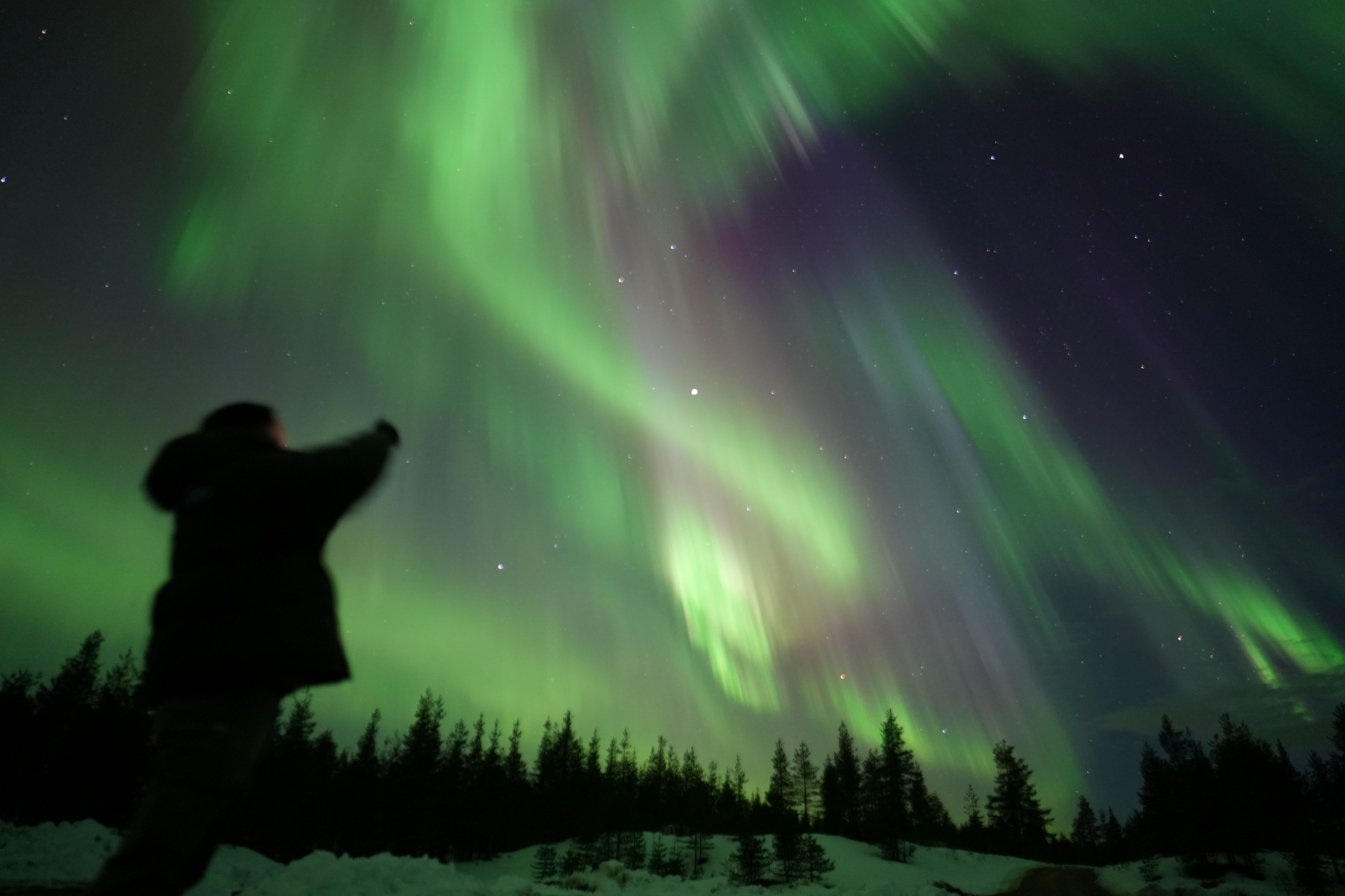 Person admiring vibrant northern lights in Rovaniemi, Lapland, Finland