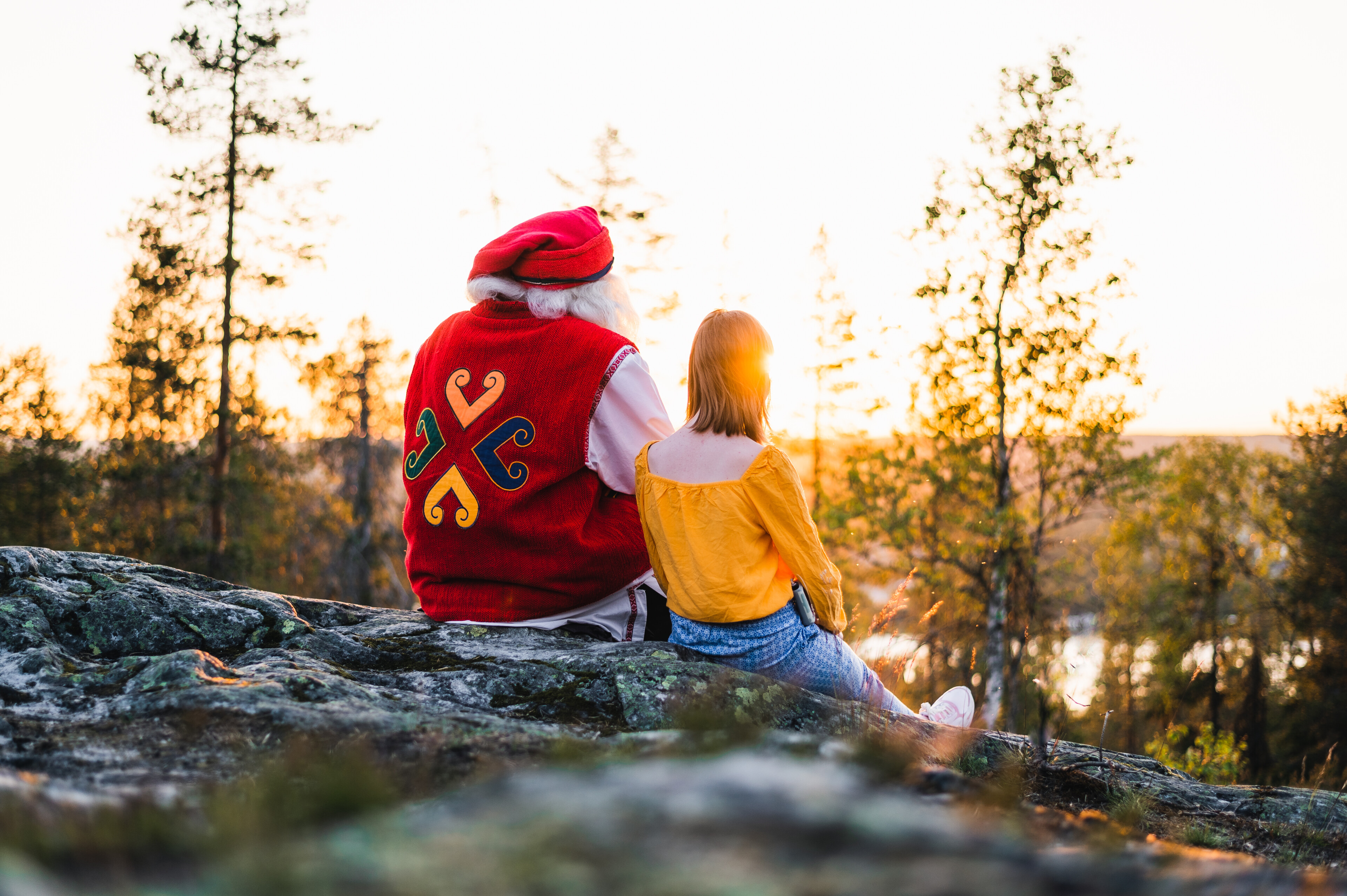Santa Claus and a girl in Ounasvaara with a view during summer and the midnight sun in Rovaniemi, Lapland, Finland.