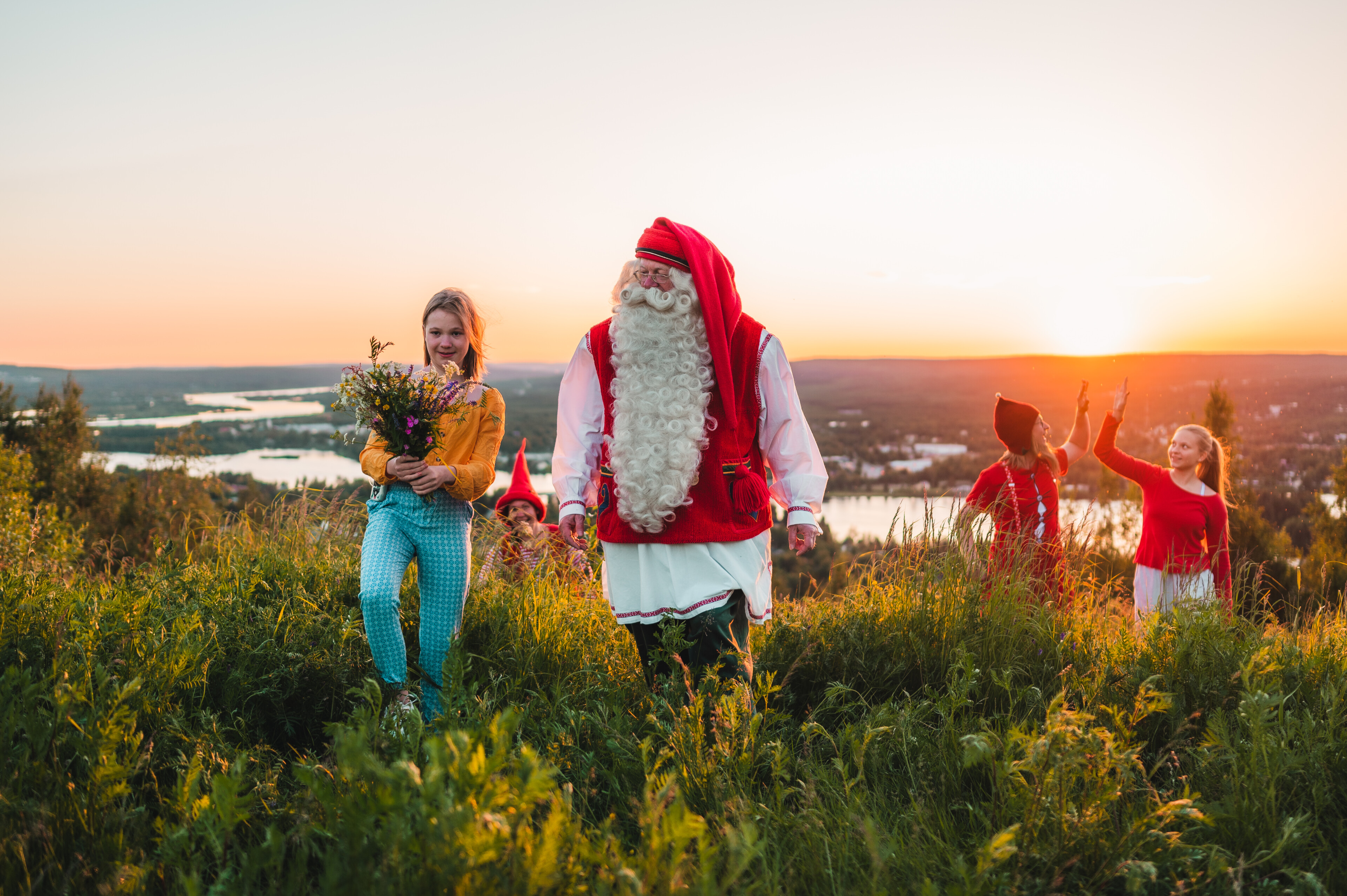 Santa Claus and a girl in Ounasvaara with a view during summer and the midnight sun in Rovaniemi, Lapland, Finland.