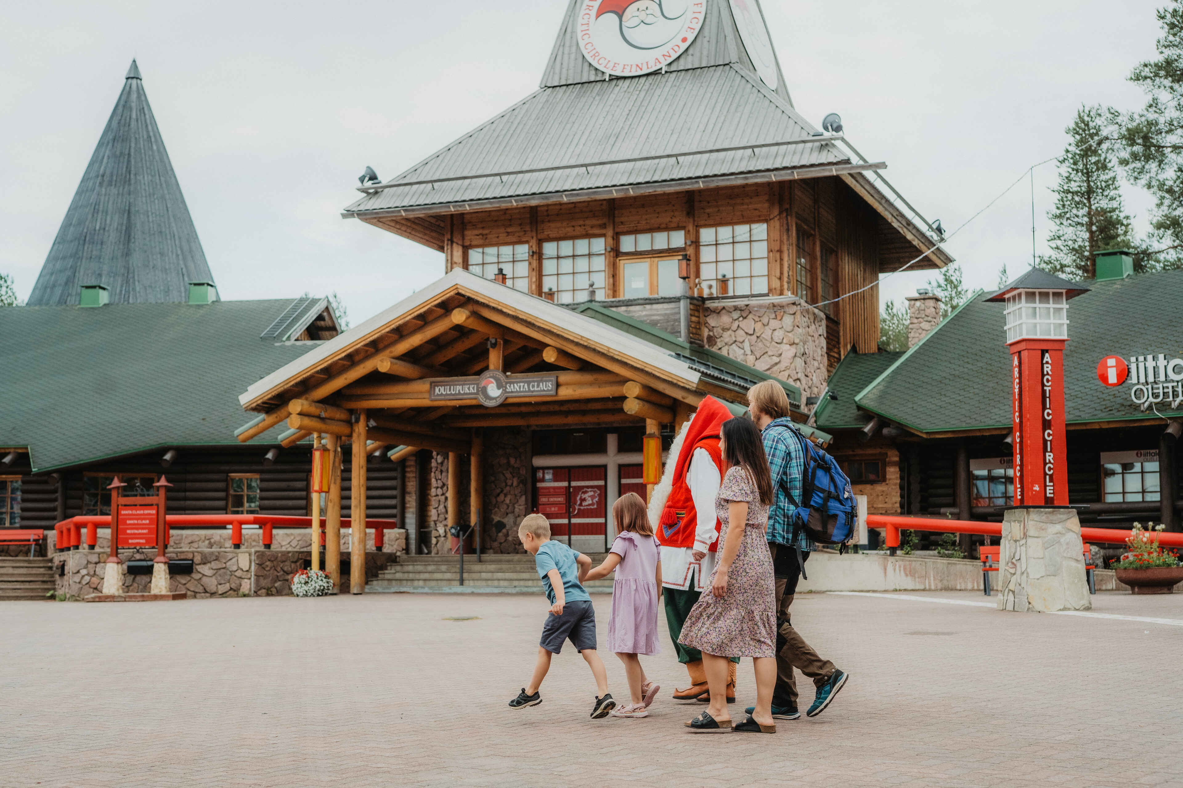 Santa Claus and a family in Santa Claus Village at the Arctic Circle during summer in Rovaniemi, Lapland, Finland.