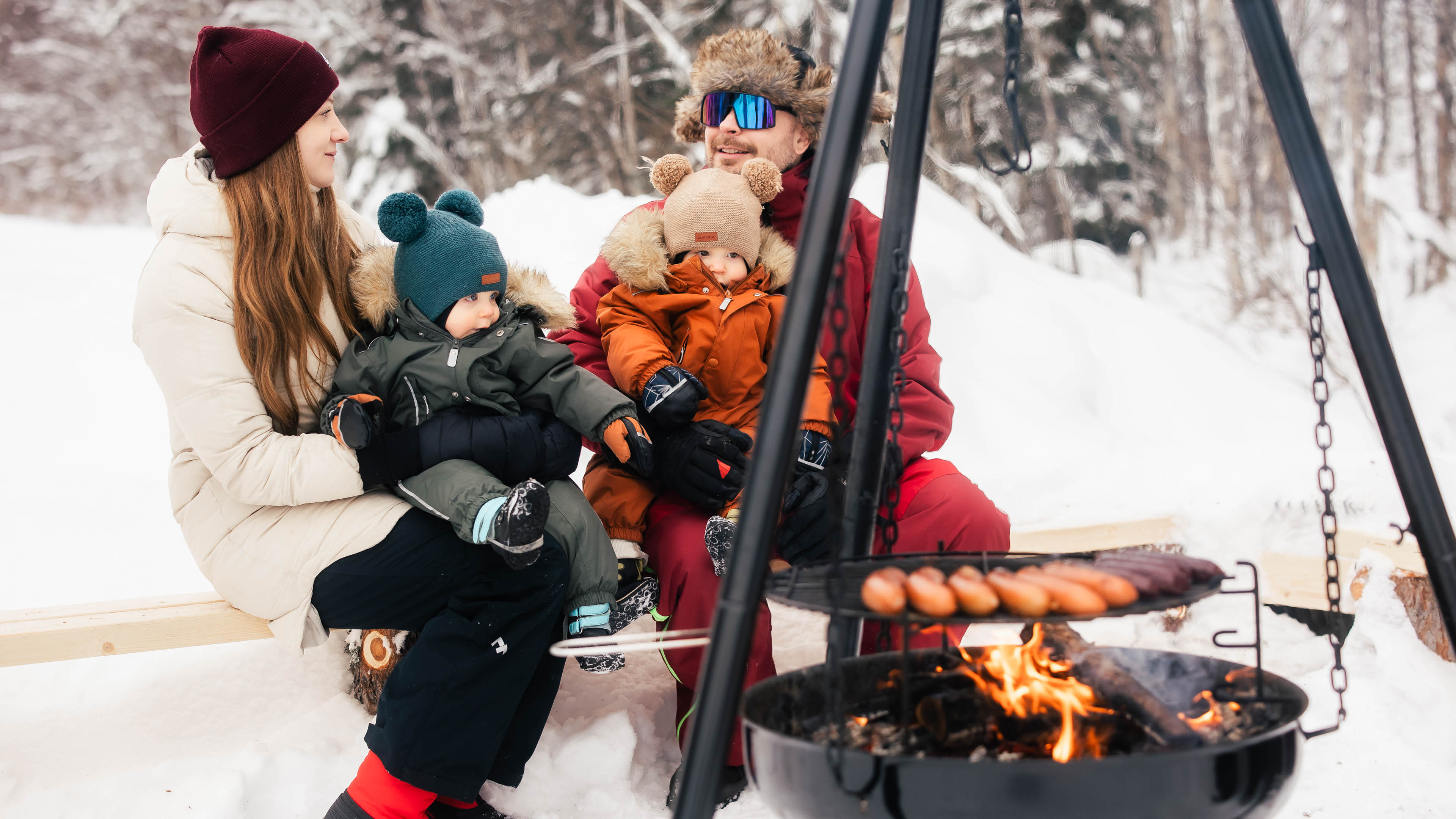Family enjoying sausages by fire at Arctic Park, Rovaniemi, Lapland, Finland