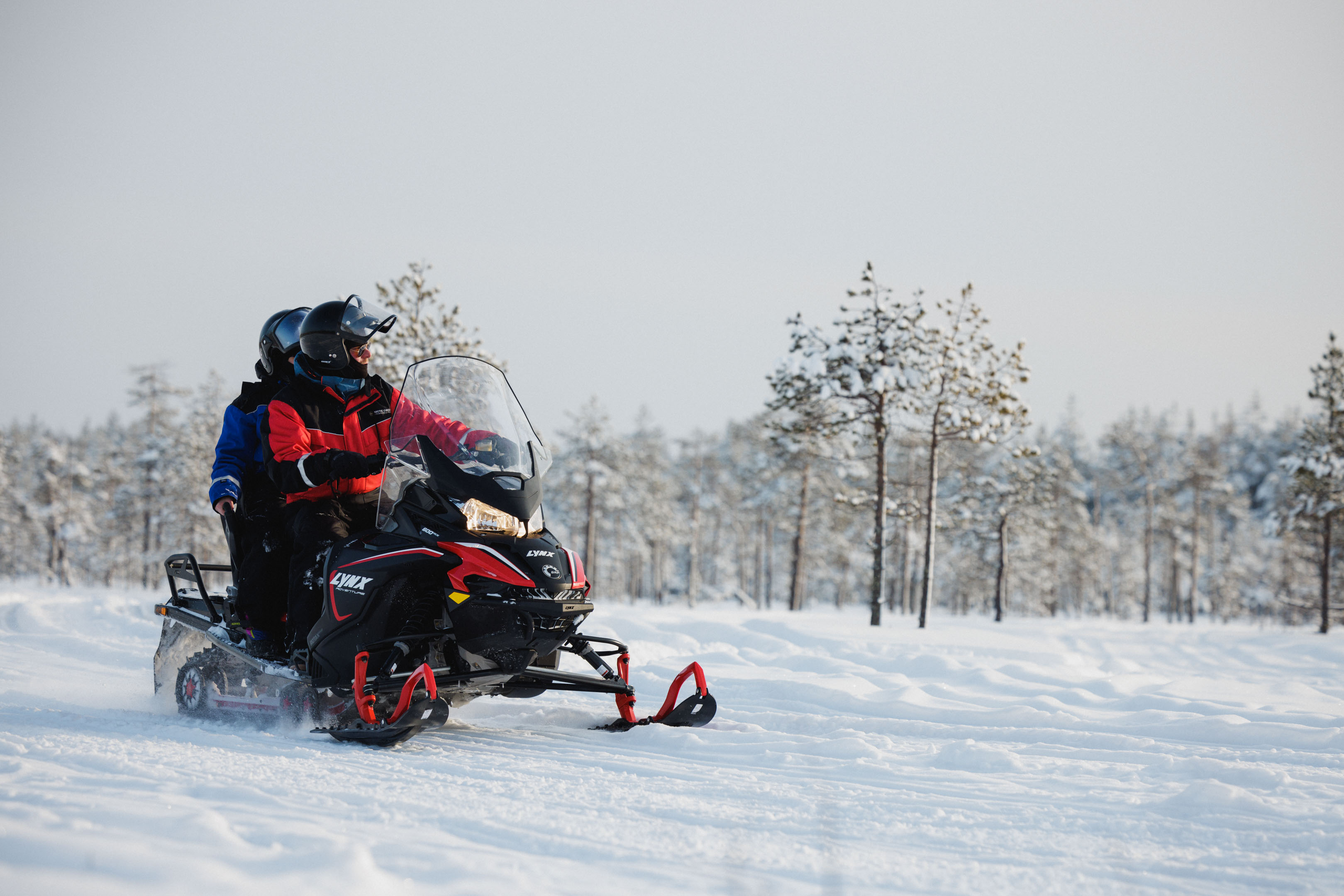 two persons on a snowmobile in wintery forest in Rovaniemi, Lapland, Finland