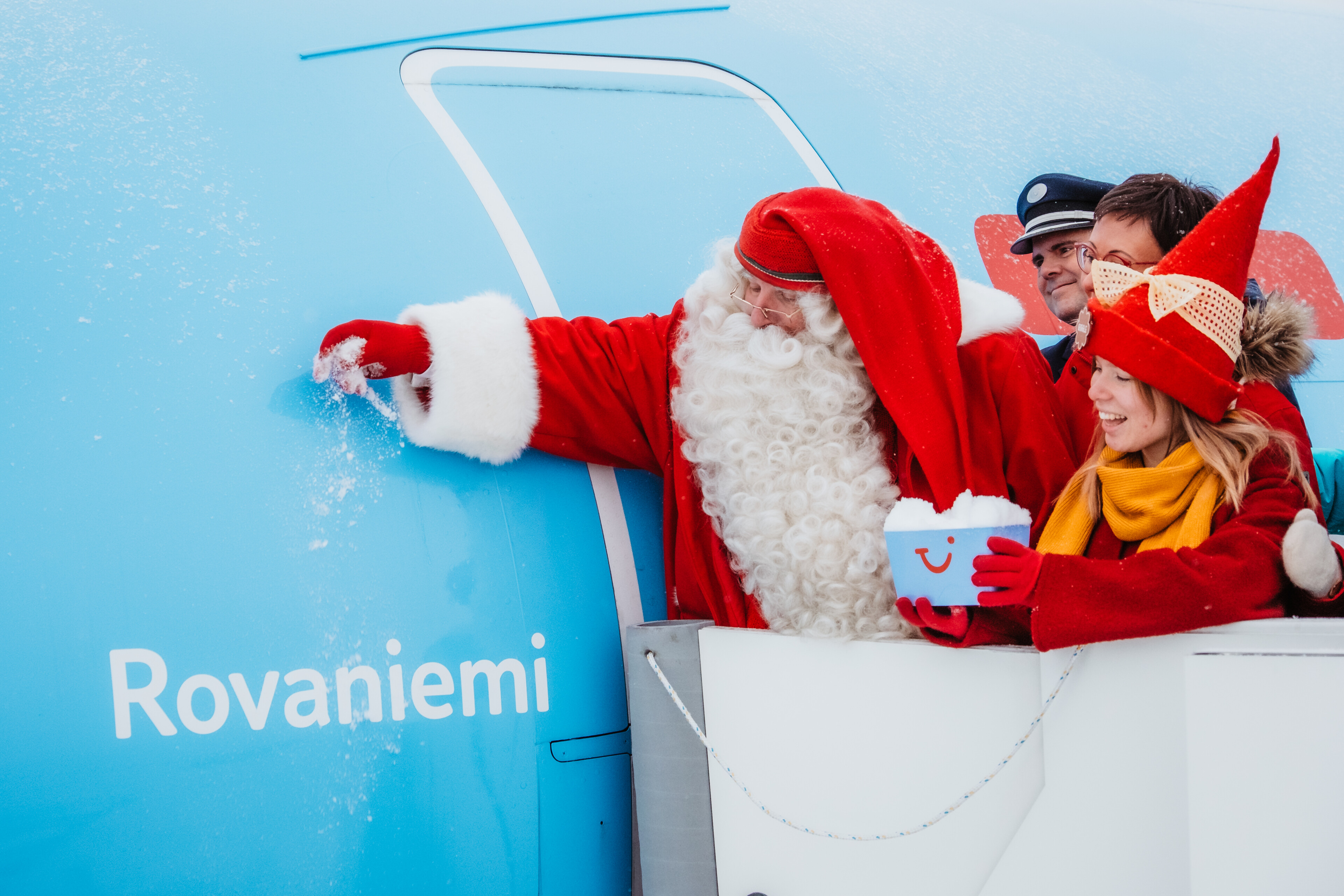 Joulupukki ripottelemassa lunta TUI:n lentokoneen päälle, joka on nimetty Rovaniemeksi Rovaniemen lentokentällä, Lapissa.