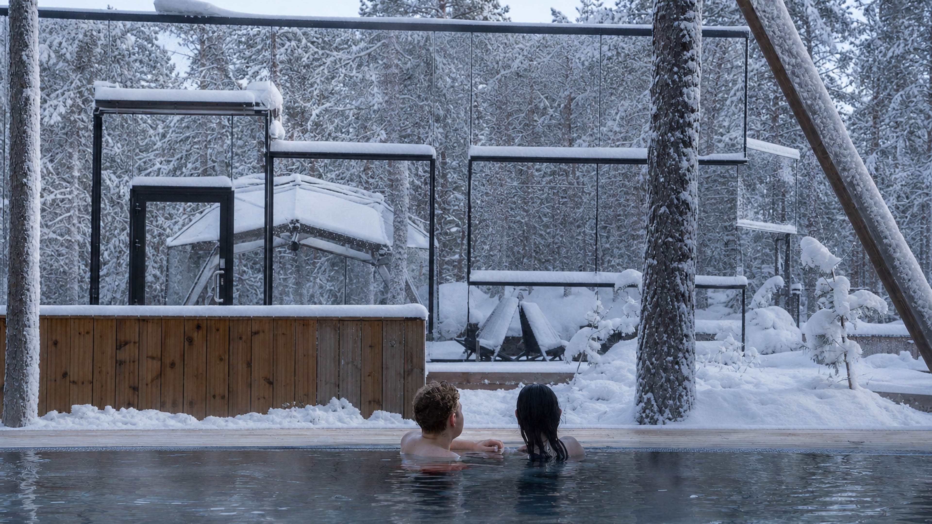 Couple relaxing in snowy spa pool at Arctic Forest Spa, Invisible Forest Lodge