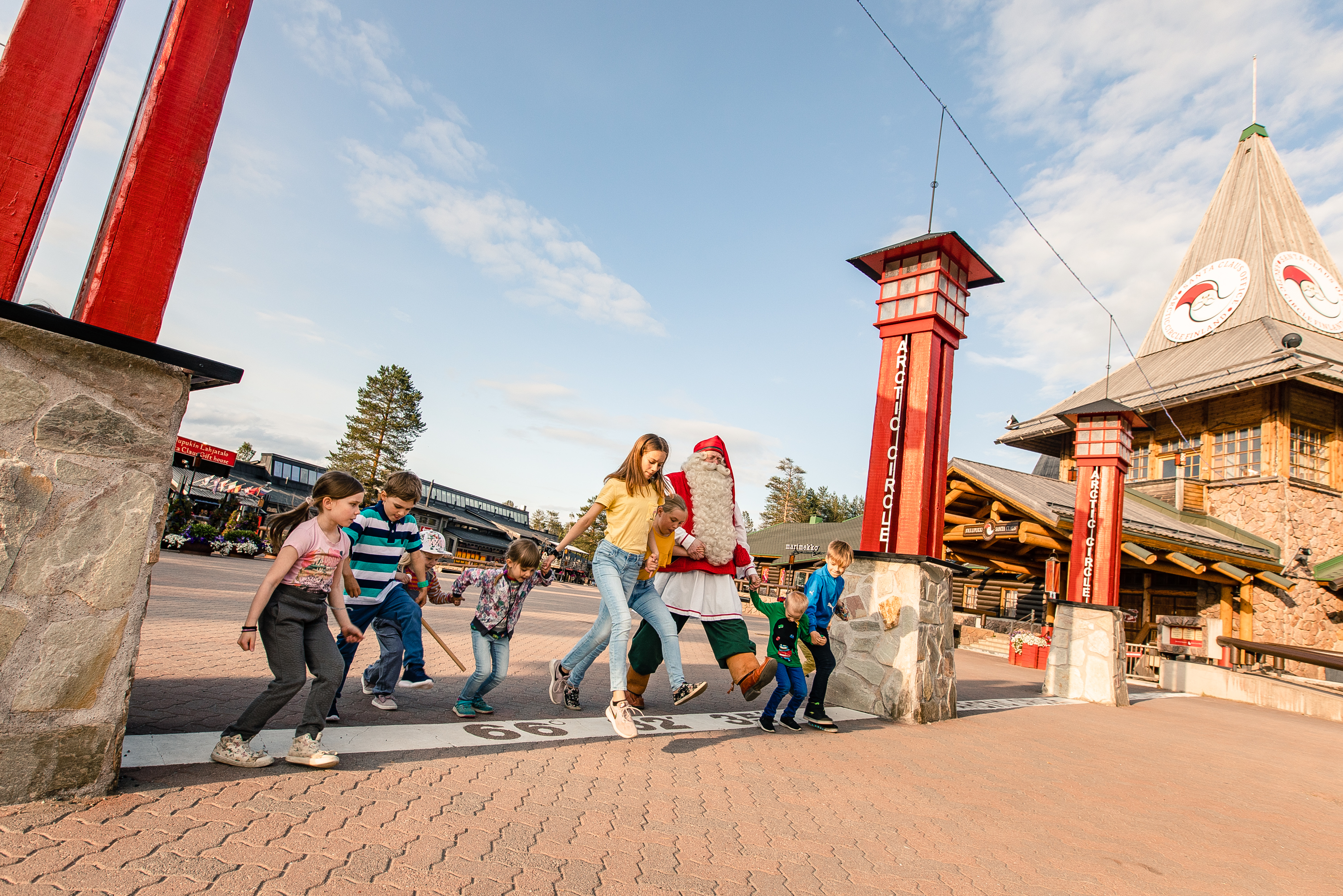 Santa Claus playing with kids and crossing the Arctic Circle in Santa Claus Village, Rovaniemi, Lapland, Finland, during summer.