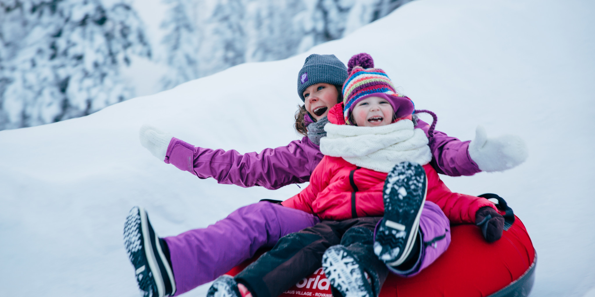 Mother and daughter snowtubing in Santa Claus Village in Rovaniemi, Lapland, Finland